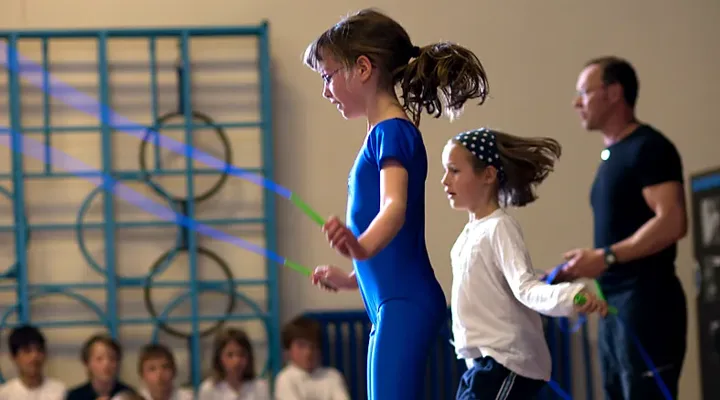 Two pupils skip side by side in a PE lesson while a skip-hop coach helps