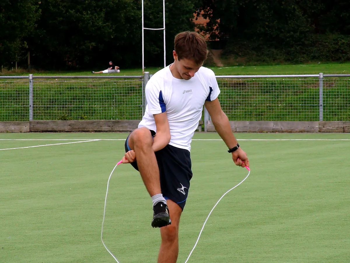 An adult skipping with a high knee lift on a sports pitch
