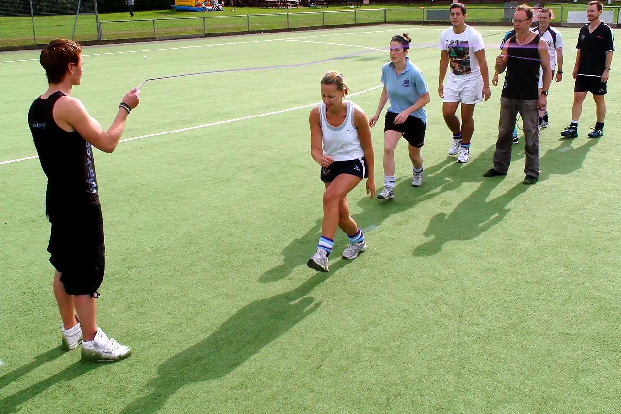 A group of adults run into a long rope outdoors