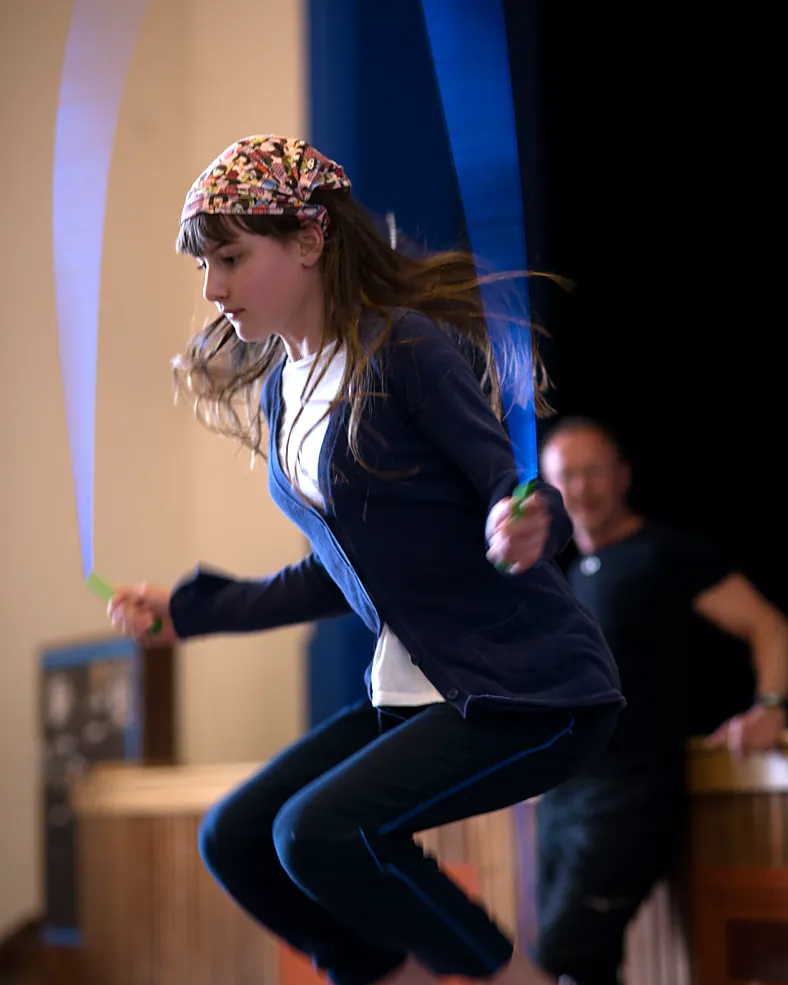A primary school girl jumps high as her skipping rope spins in the school hall