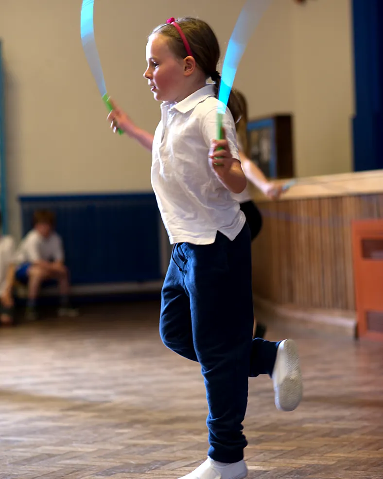 A young girl practises a basic skipping bounce in the school hall