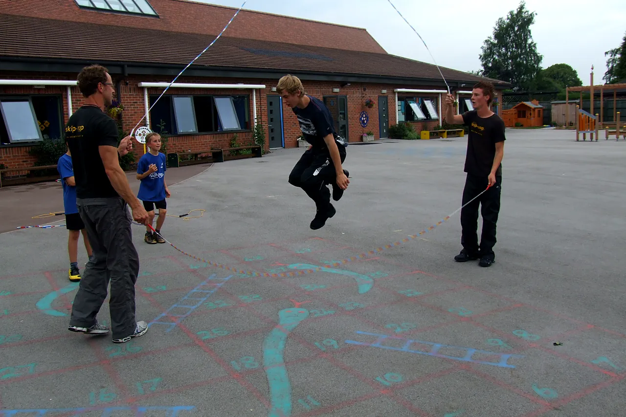 Moseley Primary pupils jump a long rope turned by skip-hop coaches in the school playground