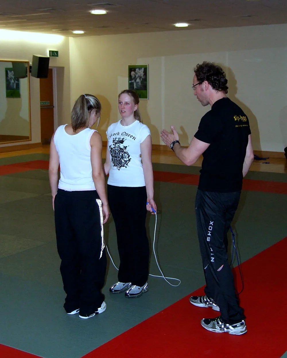 A skip-hop coach shows two members of staff how to hold and turn the rope