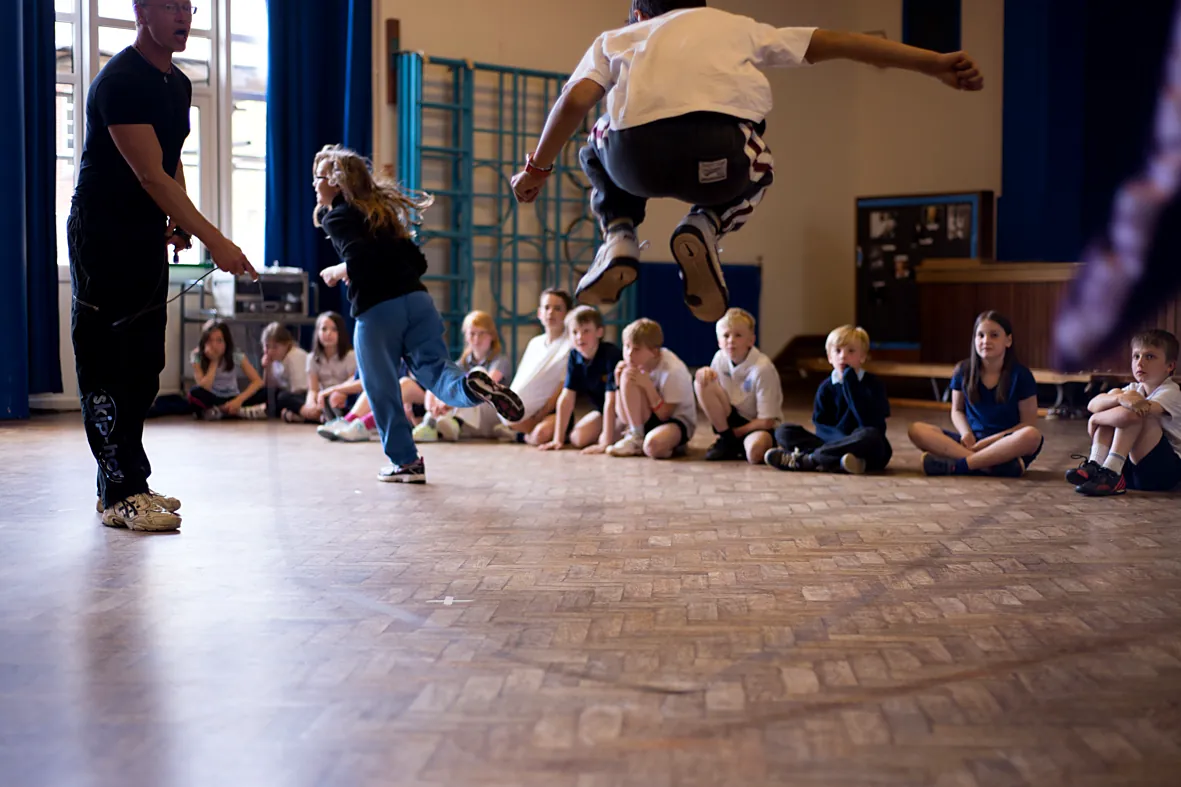 Pupils skip in the school hall during a skip-hop session while their class watches